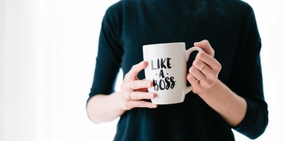 female entrepreneur holds mug with words like a boss